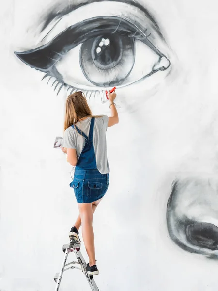 Graffiti Artist Drawing face of beautiful woman with paint on Street Wall. Female working with brush. Urban Outdoors Art Concept — Stock Photo, Image