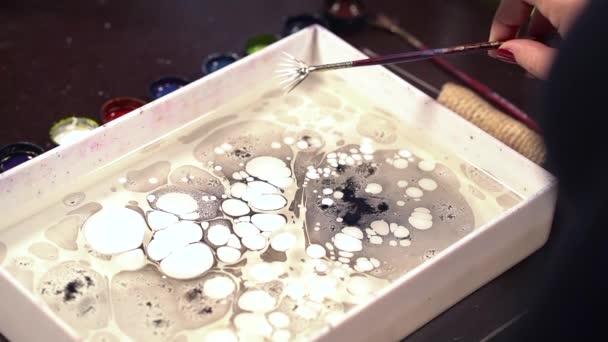 Splashing white color. Ebru is art of painting on liquid water surface. Paper marbling. Woman drawing with brush and black paint. Close up hand. Hobby, arts, culture concept — Stock Video