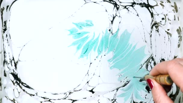 Papel de mármol Ebru es una especie de pintura de Oriente, cuyo producto es una imagen abstracta creada en el agua. Dibujo de mujer con pincel, pinturas azules y negras. De cerca la mano . — Vídeos de Stock