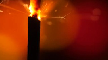 Maytap turuncu üzerinde. Barutun derin, karanlık arka plan karşı atış kıvılcım. Yanan sigorta veya bengal ateşi göl kenarında. Mojo tarzı boyama. Noel maytap aydınlatma