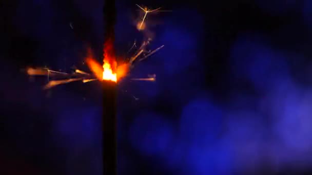 Wunderkerze über Blau. Pulverfunken schossen vor dunklem Hintergrund. Brennende Lunte oder bengalisches Feuer isoliert. Mojo-Stil Färbung. Weihnachtsfunkel entzünden — Stockvideo