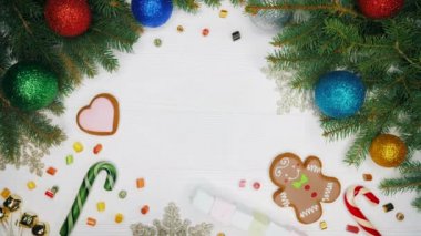 Üstten görünüm. Kadının ellerini koyar Ladin ve yabani gül çilek delikanlı ile dekore edilmiş craftool kağıt sarılı hediye. Noel şeyleri, çelenk, zencefilli, lolipop ile dekore edilmiş ahşap beyaz masa.