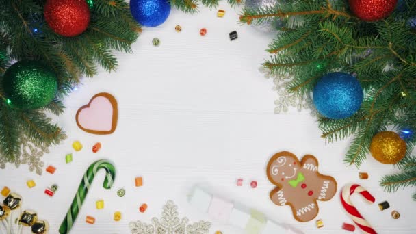 女の子の手エメラルド紙で包まれた贈り物を置くし、それを取る。クリスマスの装飾 - ジンジャーブレッド、マシュマロ、キャンディーと白い木製のテーブル。新年お祭り気分 — ストック動画