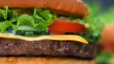 Büyük iştah açıcı burger et pirzola, sebze, peynir, salata ve sos ile. Hamburger diğer yemek arka plan üzerinde yakından görmek döner. Sağlıksız lezzetli yiyecek konsepti.