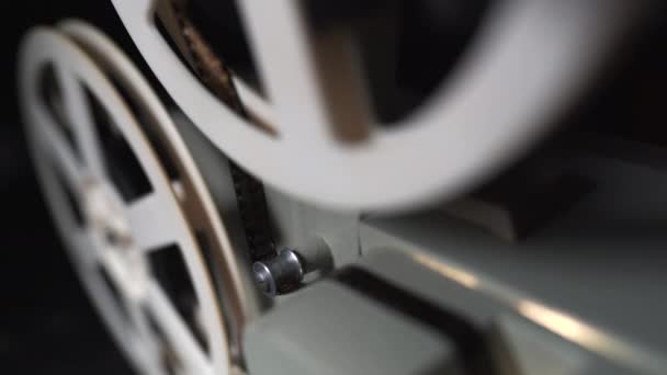 Close-up van een haspel. Oude 8 film mm projector weergegeven: film's nachts in een donkere kamer. Slow-motion. Vintage retro objecten, cinematografische concept. — Stockvideo