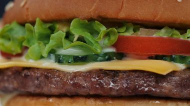 Makro görünümü sulu biftek burger katmanların ayrıntılı. Göğsü, soğan, sebze, eritilmiş peynir, marul, sos ve tepesinde susam. Hamburger döner. Önemsiz lokanta kavramı.