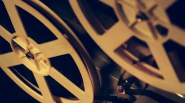 Film dönen makaraları görünümü kapatın. Vintage nesneleri Sinematografı kavramı. Karanlık odada oynayan retro film projektör. Eski moda antika süper 8mm film projektör