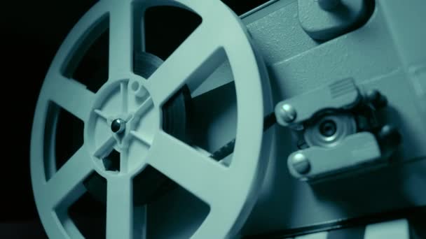劇的な青い照明とセレクティブ フォーカス フィルム映写機。レトロな映画生産の静物画。映画製作のコンセプトです。古い 8 mm プロジェクターをオフにします。フィルム リールのクローズ アップ. — ストック動画