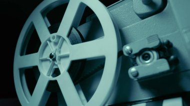 Dramatik mavi aydınlatma ve seçici odak ile film projektör. Retro film üretim natürmort. Film yapma kavramı. Eski 8mm projektör dönme uzakta. Bir makara ile bir film Close-up