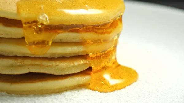 Vue rapprochée du miel ou du sirop d'érable qui goutte sur les crêpes sucrées. Délicieux, sain petit déjeuner américain. Concept de boulangerie fraîche — Photo