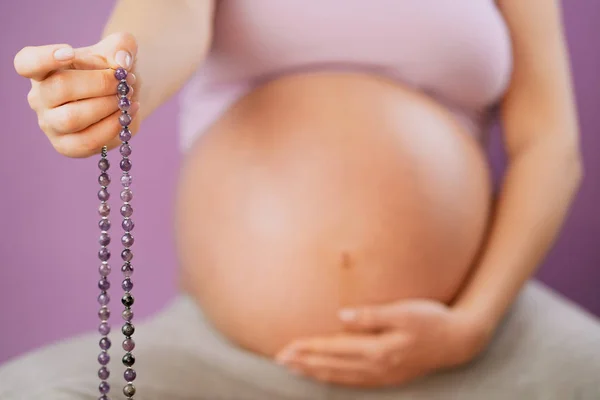 Έγκυος γυναίκα, φωτισμένο χέρι κλείστε επάνω, μετράει Μάλες, σκέλη των πολύτιμων λίθων σφαιρίδια που χρησιμοποιούνται για τη διατήρηση καταμέτρηση κατά τη μάντρα διαλογισμοί σε ροζ φόντο. Κορίτσι προσεύχεται. — Φωτογραφία Αρχείου