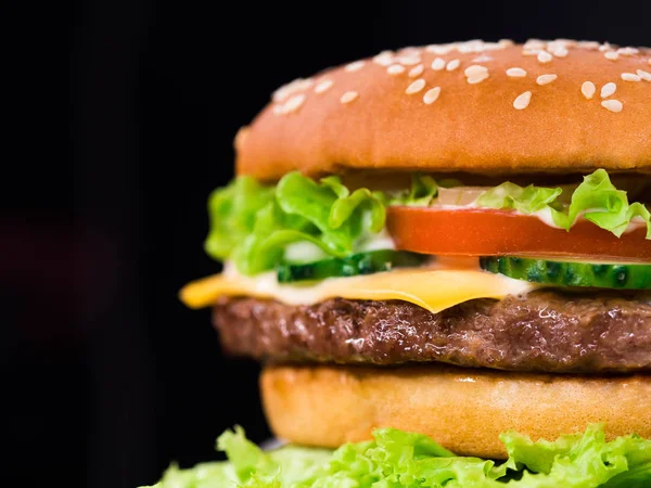 Siyah arka plan üzerine taze nefis ızgara Burger. Et patty, domates, salatalık, marul ve susam tohumu. Fast food kavramı. abur cubur yaşam tarzı