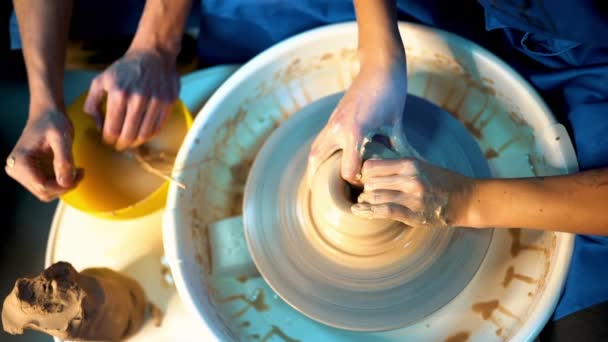 Overhead view of working process of teacher and student at potters wheel in art studio. Unknown craftsman creates jug. Focus on hands only. Small business, talent, inspiration concept — Stock Video