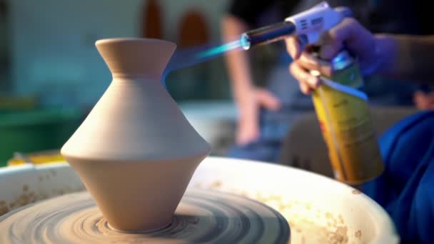 Craftsman finishes the creation of clay jug in his workshop. Man burns product using gas jet flame burner gun. Crafting, artwork, handmade concept. Slow motion — Stock Video