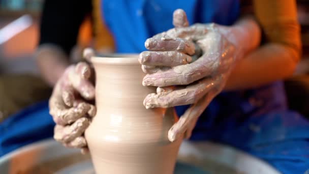 Des mains de potier et sa étudiante. Homme et femme travaillent ensemble, créant un produit en argile sur une roue de potier. Poterie traditionnelle, professeur montre les bases de la poterie en atelier d'art — Video