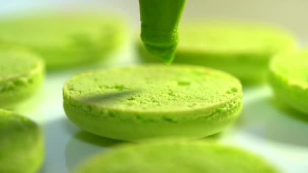 Faire des macarons verts à la pistache, presser et ajouter la crème de remplissage du sac à pâtisserie. Macarons - délicieux et beau dessert français. Cuisine, nourriture et cuisson, concept de pâtisserie . — Video