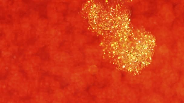 Gold ink in water on red. Glitter paint reacting creating abstract cloud formations. Shining sparkles. Can be used as transitions,added to modern projects,art backgrounds. — Stock Video