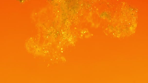 Glitter in water. Gold paint on orange reacting in water creating abstract cloud formations.Can be used as transitions,added to modern projects,art backgrounds, anything with creative twist. — Stock Video