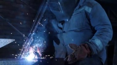 Metal kaynak yakın çekim. Koruyucu maske demir merdiven üzerinde çalışan erkek kaynakçı. Endüstriyel yapı kavramı. Modern kaynak makinesinden kıvılcım. Ağır çekim.