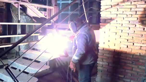 Metal kaynak. Koruyucu maske demir merdiven üzerinde çalışan erkek kaynakçı. Endüstriyel yapı kavramı. Modern kaynak makinesinden kıvılcım. Ağır çekim — Stok video
