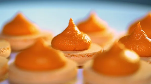 Macaron al pistacchio all'arancia, spremitura e aggiunta di ripieno di panna dal sacchetto di pasta. Macaron - dessert francese delizioso e bello. Cottura, cibo e cottura, concetto di pasticceria . — Foto Stock
