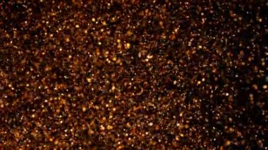 Bakır parçacıklar su altında karışık hareket ederler. Altın arka plan. Altın parlayan parlak siyah. Güzel soyut doku. Projelerde geçişler olarak kullanılabilir.
