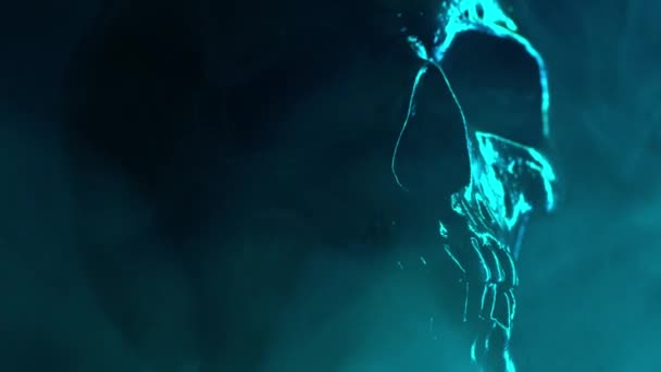 Модель черепа человека вращается на тёмном фоне с неоновой красочной бирюзовой подсветкой и дымом. Празднование Хэллоуина, гламур, концепция стиля — стоковое видео