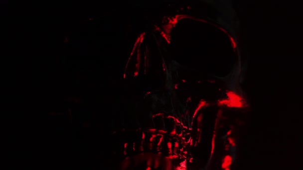 La tête du crâne noir tourne sur fond sombre avec une lumière rouge sanglante. Fête d'Halloween, glamour, concept de style — Video