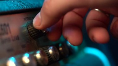Bir gitar amplifikatör üzerinde kontrol panelinin görünümü. Tumblers, düğme ve düğmeler. Erkek el açın ve amfi üzerinde müzik hacmi artan. Renkli neon ışık