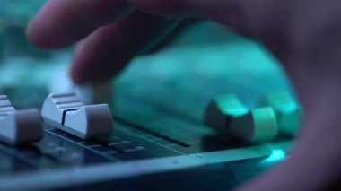 Müzik konserinde Mikser konsolunda fader ile çalışan ses mühendisi el. Görünümü yakın. Renkli neon ışık