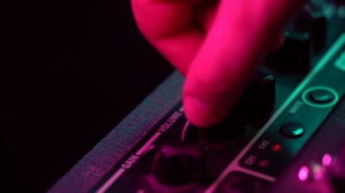 Bir gitar amplifikatör üzerinde kontrol panelinin görünümü. Tumblers, düğme ve düğmeler. Erkek el açın ve amfi üzerinde müzik hacmi artan. Renkli neon ışık