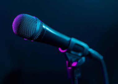 Renkli pembe ve turkuaz ışık ile siyah arka plan üzerinde mikrofon. Müzik, konser konsepti.