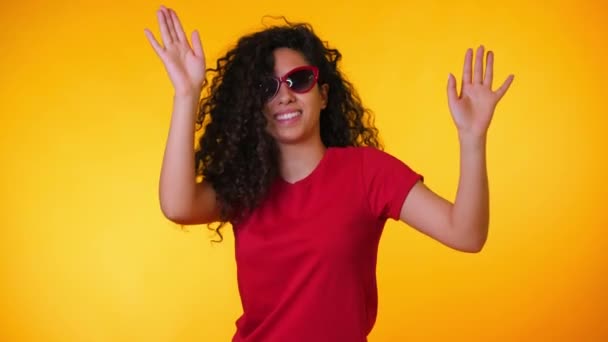 La chica se mueve al ritmo de la música. Woamn con pelo rizado bailando sobre fondo amarillo. Mujer divirtiéndose. Ella sonriendo, el pelo ondeando maravillosamente. Increíbles imágenes positivas . — Vídeos de Stock