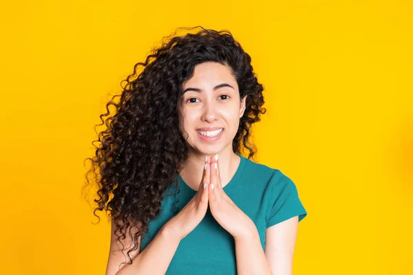 Sarı arka plan üzerinde dua yeşil t-shirt çekici İspanyol kadın. Karışık yarış kız birine yalvarıyor. — Stok fotoğraf