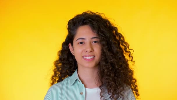 Retrato da jovem estudante hispânica com cachos no fundo amarelo. Mulher bonita na moda sorrindo para a câmera. Imagens do estúdio. Feminino em camisa, estilo casual — Vídeo de Stock