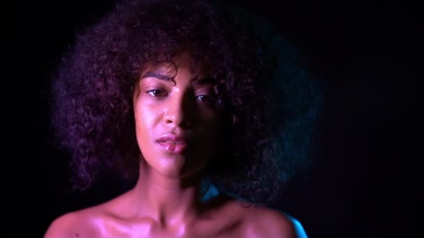 Retrato de una joven mestiza. Concepto de piel sana. Mujer linda positiva con maquillaje posando en habitación oscura sobre fondo negro . — Vídeos de Stock