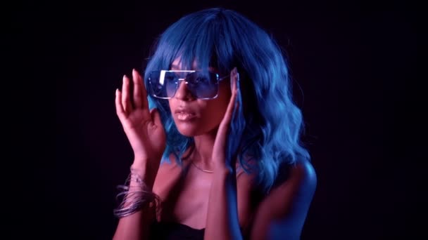 Alluring unusual girl with blue wig hair corrects her glasses. Sexy woman with perfect makeup looking at camera and smiling. Glamour, fashion concept. — Stock Video