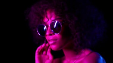 Siyah arka planda pembe Neon ışık ve ayna Gözlük Genç baştan çıkarıcı Afrikalı Amerikalı kız portre. Mükemmel makyaj kamera bakarak cazip kadın.