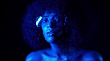Mavi Neon ışıkta gece karanlık odada poz şeffaf güneş gözlüğü ile disko seksi kadın. Genç karışık yarış Afrika kız portresi. Moda, glamour, model konsepti