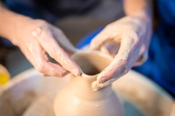 Working process of mans work at potters wheel in art studio. Unknown craftsman creates jug. Focus on hands only. Small business, talent, invention, inspiration concept