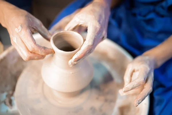 Traditional pottery making, man teacher shows the basics of pottery in art studio. Artist operates hands, which gently creating correctly shaped jug handmade from clay