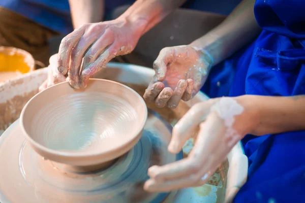 Traditional pottery making, man teacher shows the basics of pottery in art studio. Artist operates hands, which gently creating correctly shaped jug handmade from clay