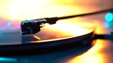 Görüntü yönetmeni vinil plak çalar ve müzik plakası boyunca uzanan bir pikap. Neon ışığı. Retro-stil dönen plak çalar. Kapat.