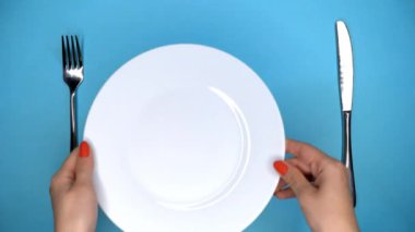 Restoran veya kafede masa ayarı. Çatal ve bıçak. Kadın eller koyar ve mavi masada beyaz plaka alır