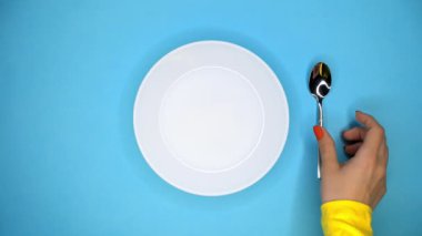 Kadın elleri koyar ve mavi masada küçük çay kaşığı alır. Restoran veya kafede masa ayarı. Yalıtılmış nesneler. Yakın görünüm.