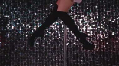 Siyah çoraplı genç striptizci gece kulübünde sırıkla cinsel olarak dans ediyor. Poledance. Pylone 'la numaralar yapan tanınmayan bir kadının yakın plan bacakları..