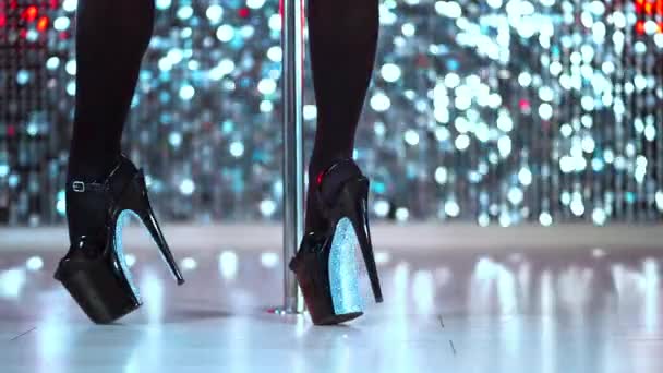 夜のメンズクラブでポールの近くのハイヒールの靴で若いストリッパーダンスや訪問者を魅了します。輝く壁の背景で踊る女 — ストック動画