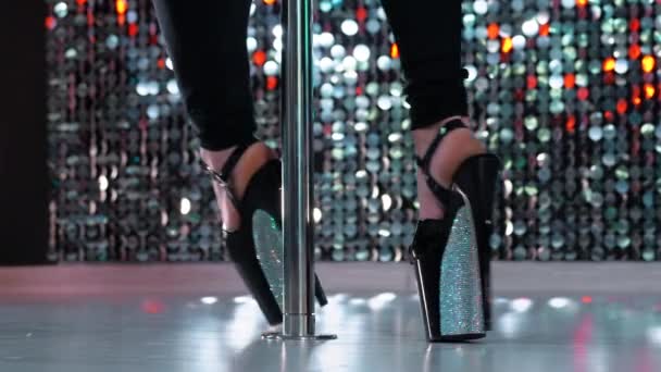 Junge sexy Striptease-Tänzerin bewegt sich in Stöckelschuhen mit Strasssteinen auf der Bühne mit Pylone im Strip-Nachtclub, Pole Dance. leuchtender Hintergrund. Tanz, Sex, Versuchungskonzept. — Stockvideo