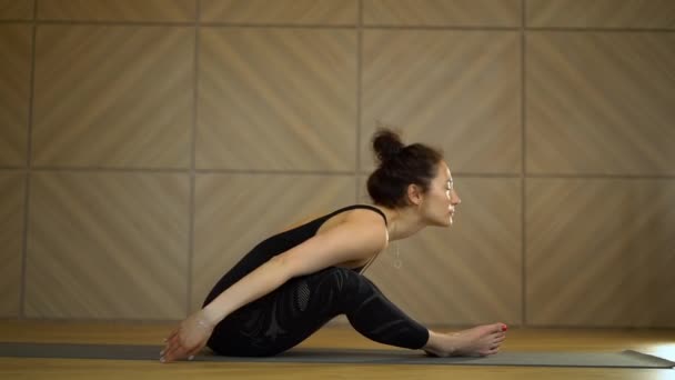 Meisje doet stretching in zittende positie. Jonge mooie vrouw beoefenen yoga in lichte minimalistische studio klasse kamer. Health lifestyle concept. — Stockvideo