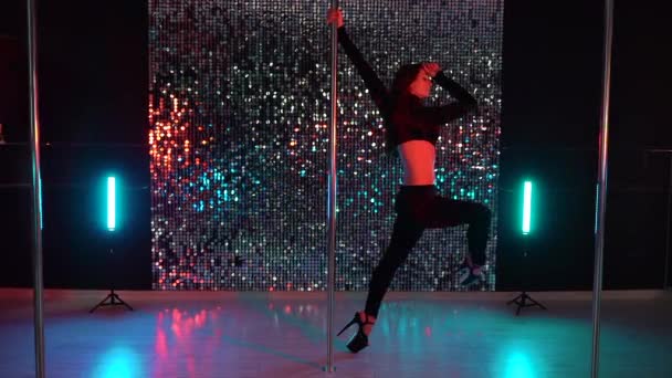 Junge sexy schlanke Frau mit langen Haaren, die in dunkel glänzendem Interieur tanzt. schönes Mädchen, das Pole Dance aufführt. .Dame mit attraktivem Körper tanzt mit Pylon — Stockvideo